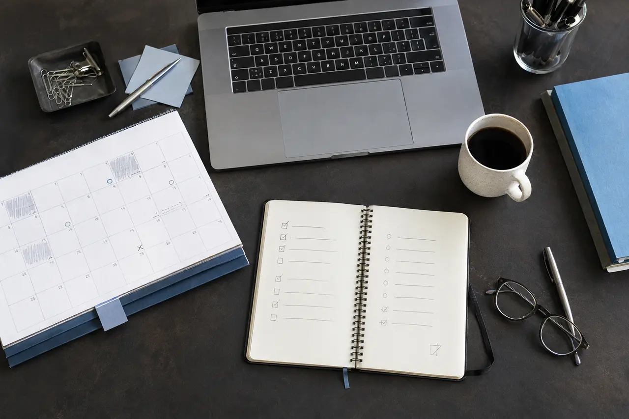 Handschriftliche Tagesplanung neben Laptop und Kalender